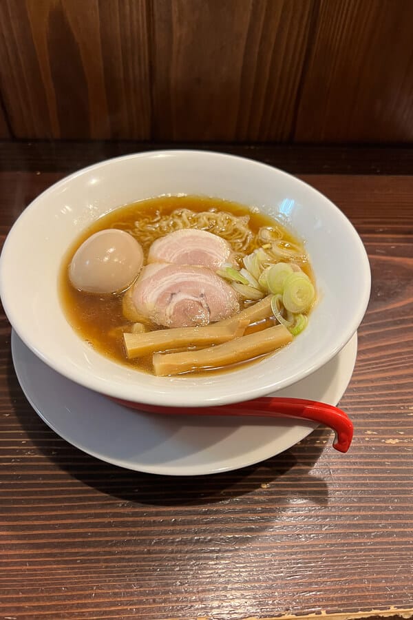 A bowl of ramen with slices of pork cutlets and boiled egg